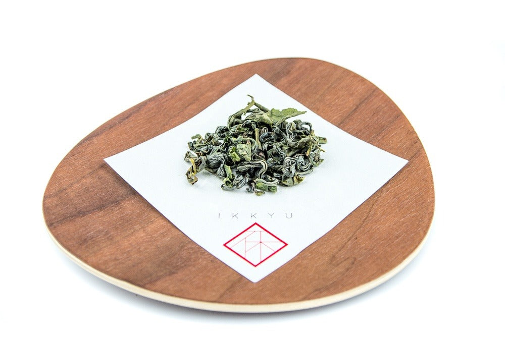 leaves of organic kamairicha on a wooden plate