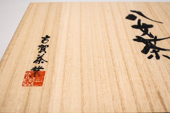 Large square wooden box with Japanese hand calligraphy written on it in black ink.
