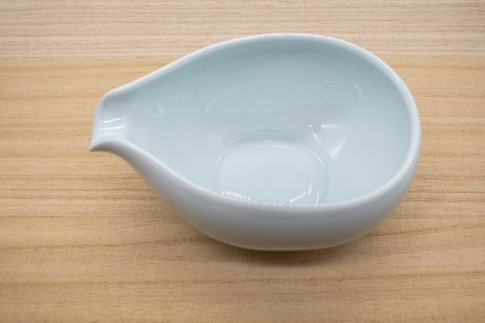 Japanese water cooler recipient in white porcelain made in Arita, Japan, made for cooling tea water to brew gyokuro green tea, placed on a wooden plank.