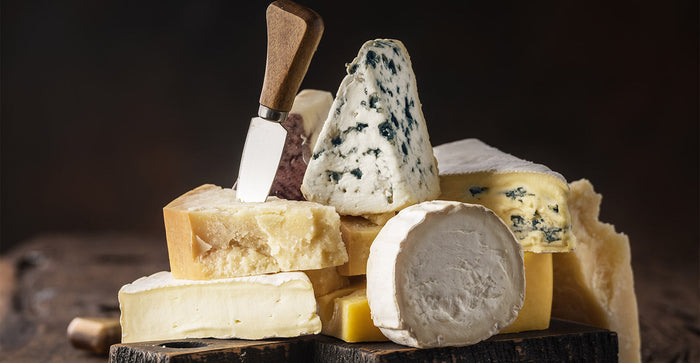 A selection of cheese on a wooden board and a knife