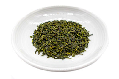 Needle-shaped and deep green premium organic gyokuro leaves from Saga, Japan, in a small round white dish.