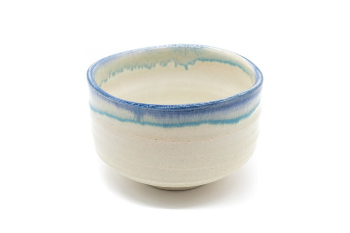 Façade d'un site Bol à Matcha blanc crème avec une glaçure bleue sur tout son pourtour irrégulier.