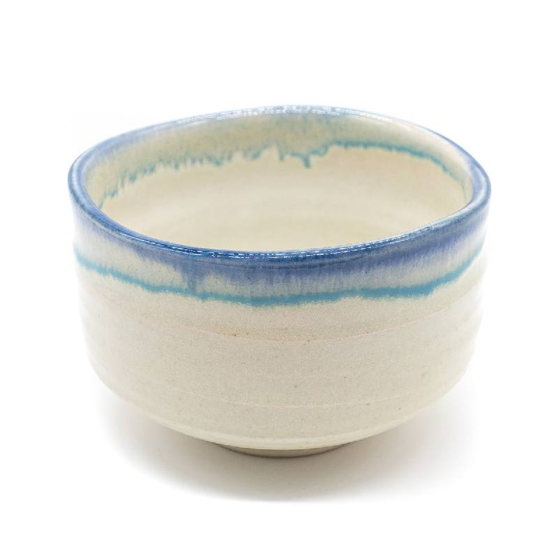 Un bol à matcha de couleur blanc crème avec une glaçure de couleur bleue sur tout le pourtour.