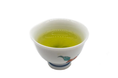 Side view of a small white porcelain cup filled with brewed premium Japanese sencha green tea.